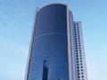 The iconic Bahrain Financial Harbour, a striking example of modern architecture with its twin towers soaring into a blue, cloud-dotted sky—home to prestigious Servcorp serviced offices,